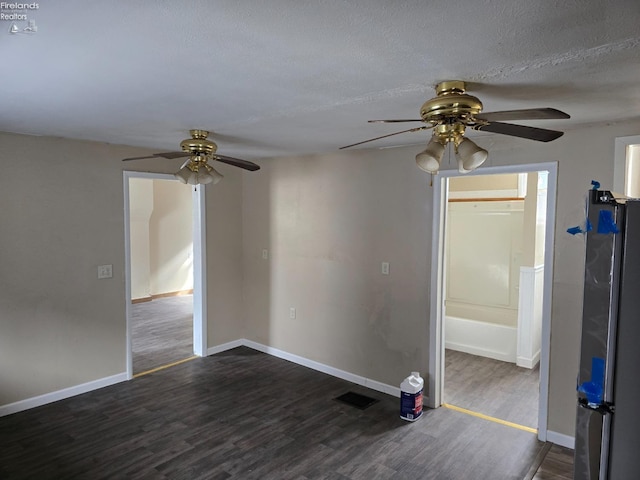 unfurnished room with dark wood-style floors, a textured ceiling, visible vents, and baseboards