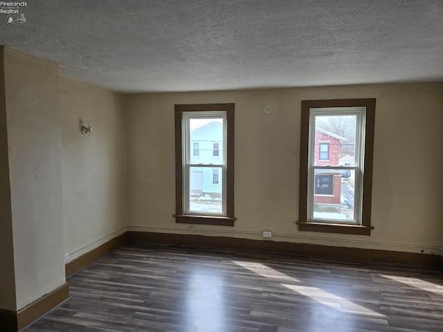 unfurnished room with a textured ceiling, baseboards, and dark wood-type flooring