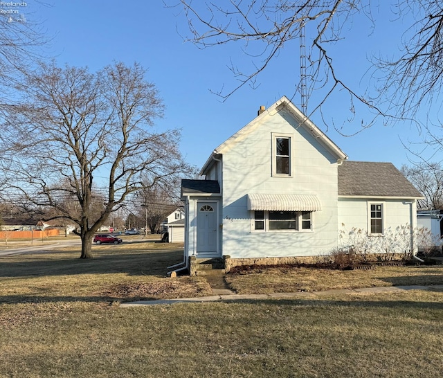 view of front facade featuring a shingled roof and a front yard