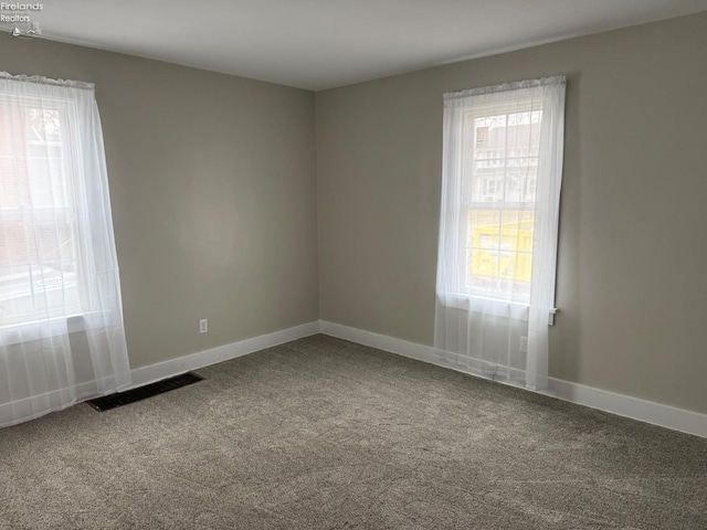 unfurnished room with carpet flooring, visible vents, and baseboards