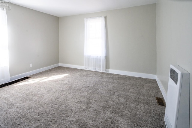 spare room with radiator heating unit, carpet, visible vents, and baseboards