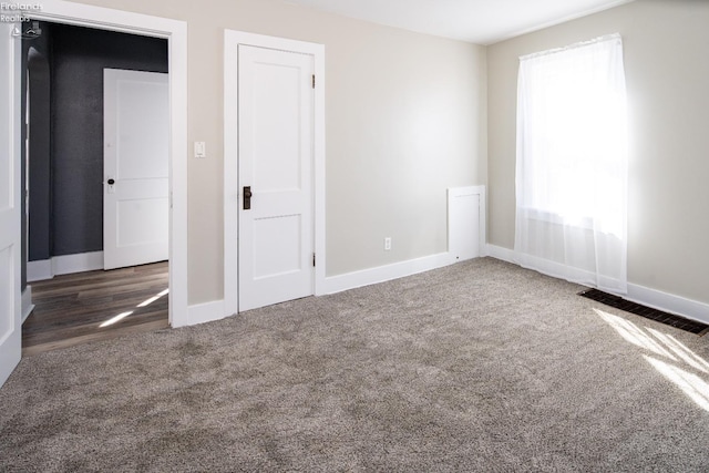 unfurnished bedroom with carpet, visible vents, and baseboards