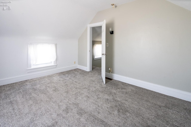 bonus room featuring lofted ceiling, carpet flooring, and baseboards