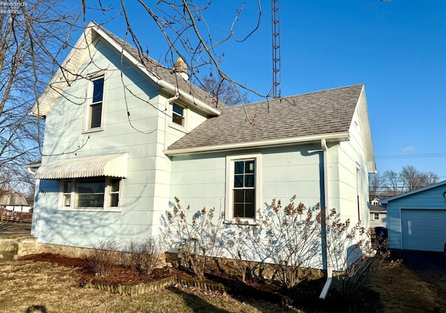 view of home's exterior featuring a shingled roof and an outbuilding