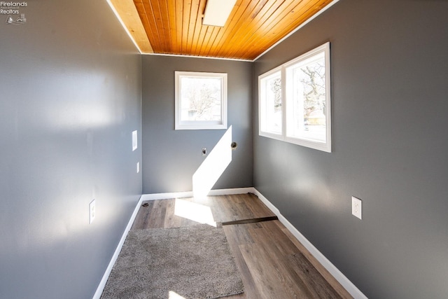 unfurnished room with a skylight, wood ceiling, baseboards, and wood finished floors