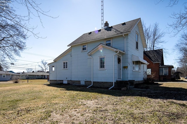 back of house featuring a shingled roof, a lawn, and a chimney