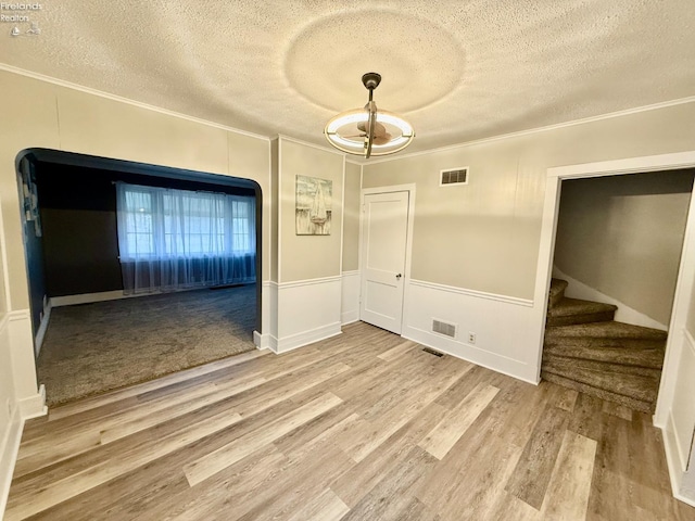 unfurnished room with crown molding, stairs, visible vents, and wood finished floors