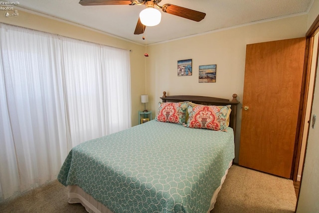 carpeted bedroom with ceiling fan and ornamental molding