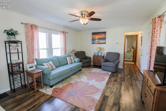 living area with baseboards, visible vents, a ceiling fan, dark wood-style floors, and ornamental molding