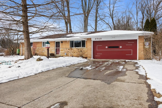 single story home featuring a garage, brick siding, and driveway