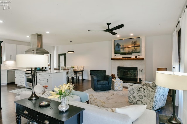 living room featuring dark wood-type flooring, recessed lighting, a fireplace, and ceiling fan