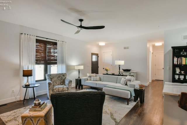 living area featuring a ceiling fan, visible vents, baseboards, and wood finished floors