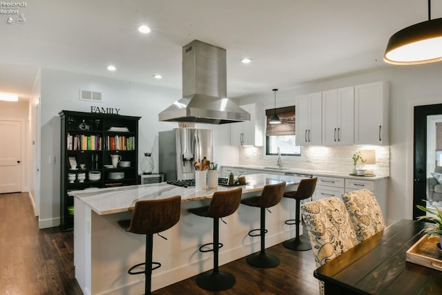 kitchen with island range hood, visible vents, white cabinets, hanging light fixtures, and a center island