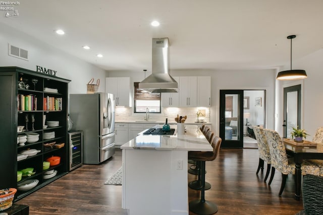 kitchen with island exhaust hood, visible vents, white cabinets, and a center island