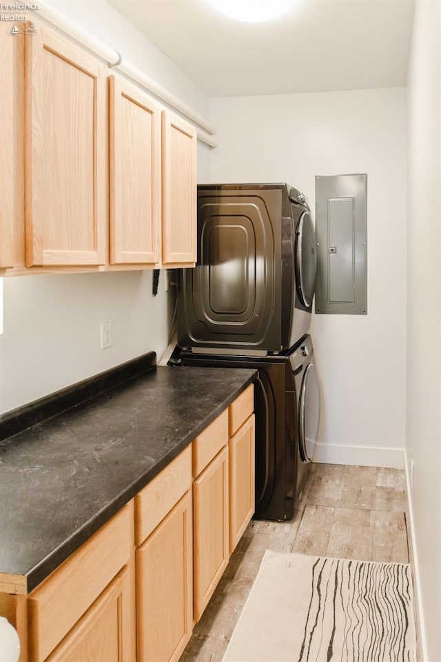 laundry area with stacked washing maching and dryer, cabinet space, electric panel, and baseboards