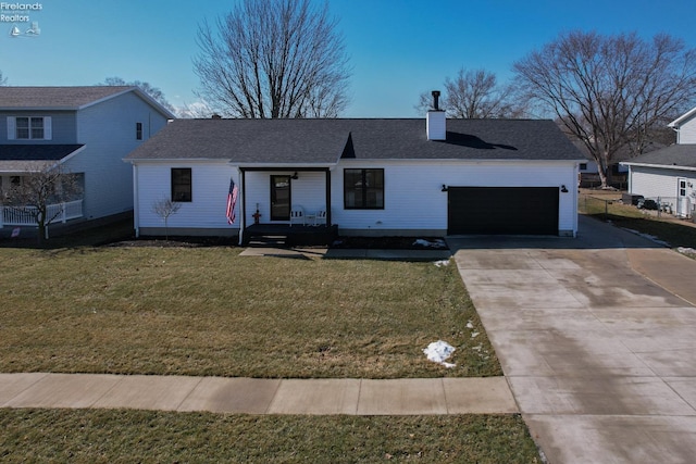 view of front facade featuring a front yard, driveway, a chimney, and an attached garage