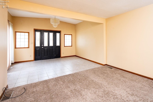 entrance foyer featuring light tile patterned floors, baseboards, light colored carpet, vaulted ceiling, and a chandelier