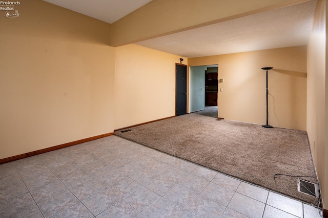 empty room featuring light tile patterned floors, baseboards, visible vents, and light colored carpet