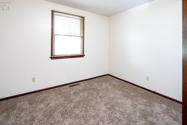 unfurnished room with carpet floors, visible vents, and baseboards