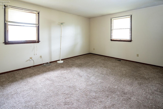 spare room featuring carpet flooring, visible vents, and baseboards