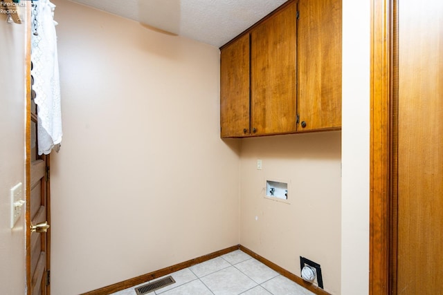 clothes washing area with light tile patterned floors, hookup for a washing machine, visible vents, cabinet space, and baseboards