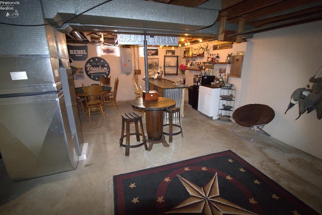 finished basement featuring electric panel, indoor wet bar, and heating unit