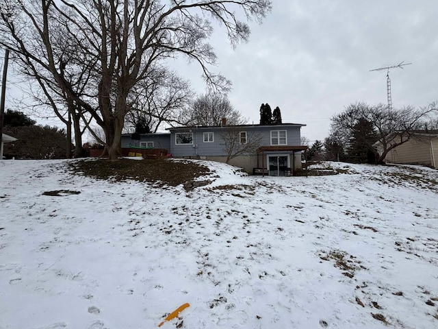 snow covered back of property featuring a garage