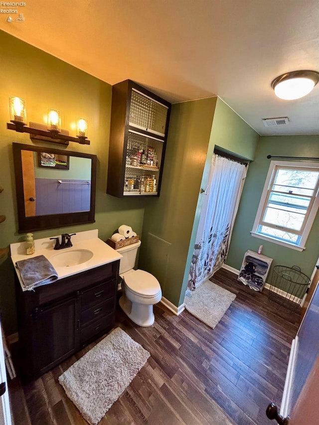 full bath featuring vanity, wood finished floors, visible vents, baseboards, and toilet