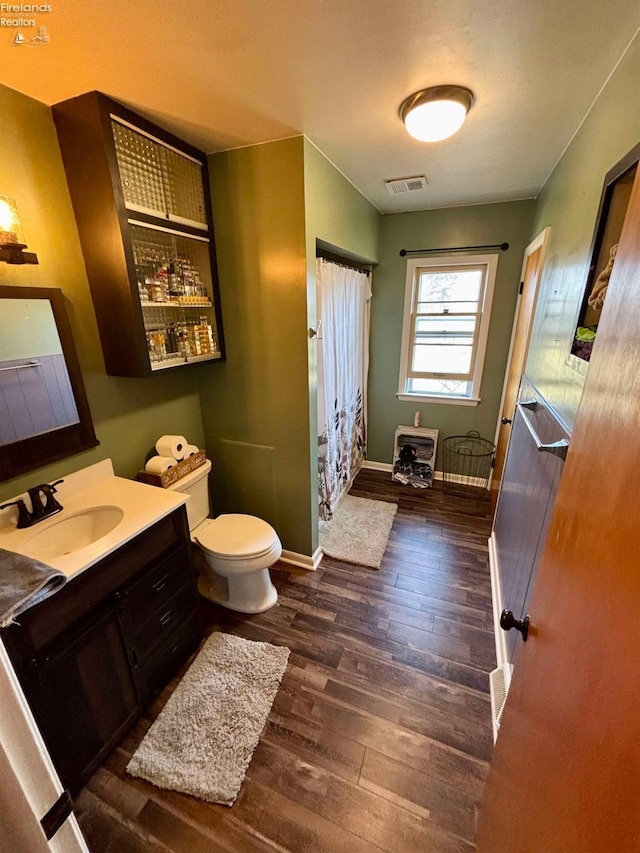 full bathroom with visible vents, toilet, wood finished floors, baseboards, and vanity