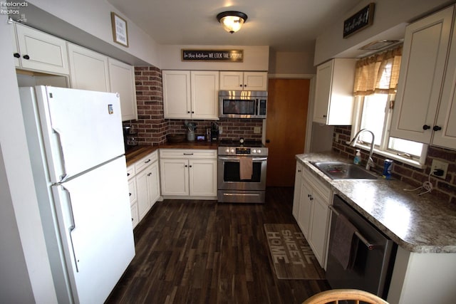 kitchen with dark wood-type flooring, a sink, tasteful backsplash, stainless steel appliances, and white cabinets