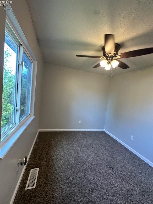 carpeted empty room featuring baseboards, visible vents, and a wealth of natural light