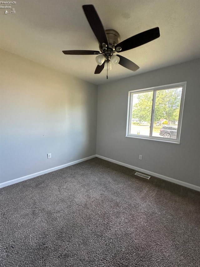 carpeted empty room featuring visible vents, baseboards, and ceiling fan