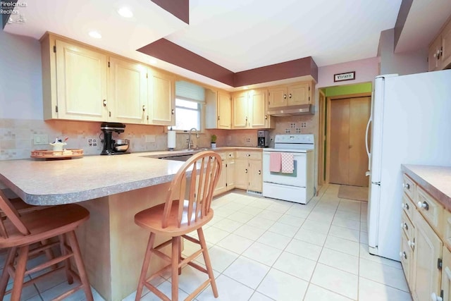 kitchen with under cabinet range hood, a peninsula, white appliances, light countertops, and backsplash