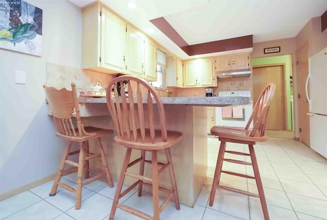 kitchen featuring a peninsula, light tile patterned floors, under cabinet range hood, and light countertops