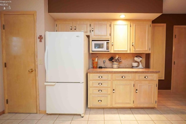 kitchen featuring light tile patterned floors, light countertops, backsplash, light brown cabinets, and white appliances