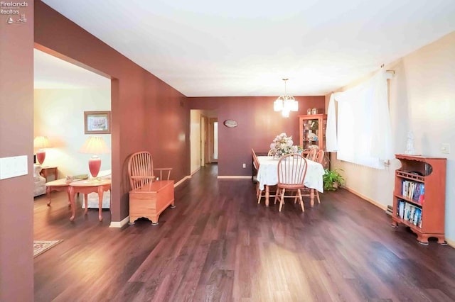 dining space with baseboards, an inviting chandelier, and wood finished floors