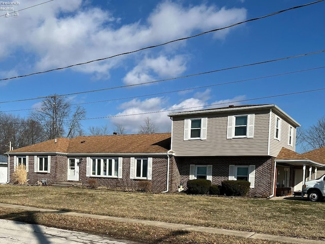 tri-level home with brick siding and a front yard