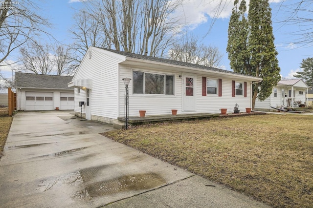 ranch-style home featuring a detached garage, a front lawn, and an outbuilding