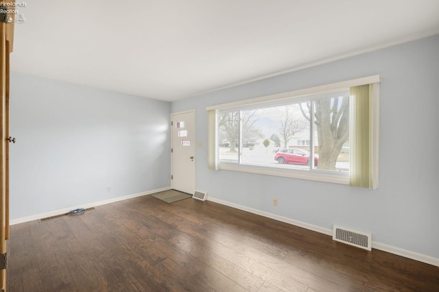 empty room featuring baseboards, visible vents, and wood finished floors