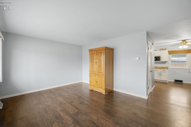 unfurnished living room featuring visible vents, dark wood finished floors, and baseboards