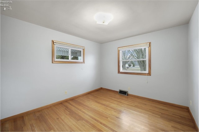 spare room featuring light wood-style flooring, visible vents, and baseboards