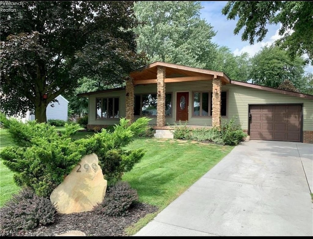 view of front of home with a garage, a front yard, concrete driveway, and covered porch