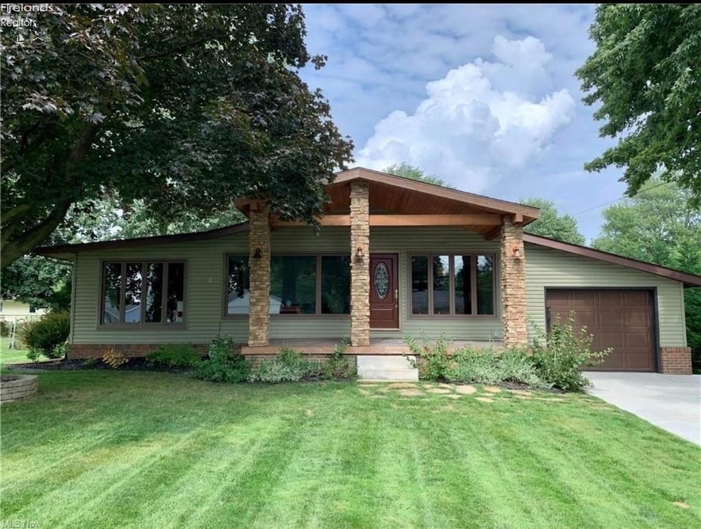 view of front of home with a garage, concrete driveway, and a front yard