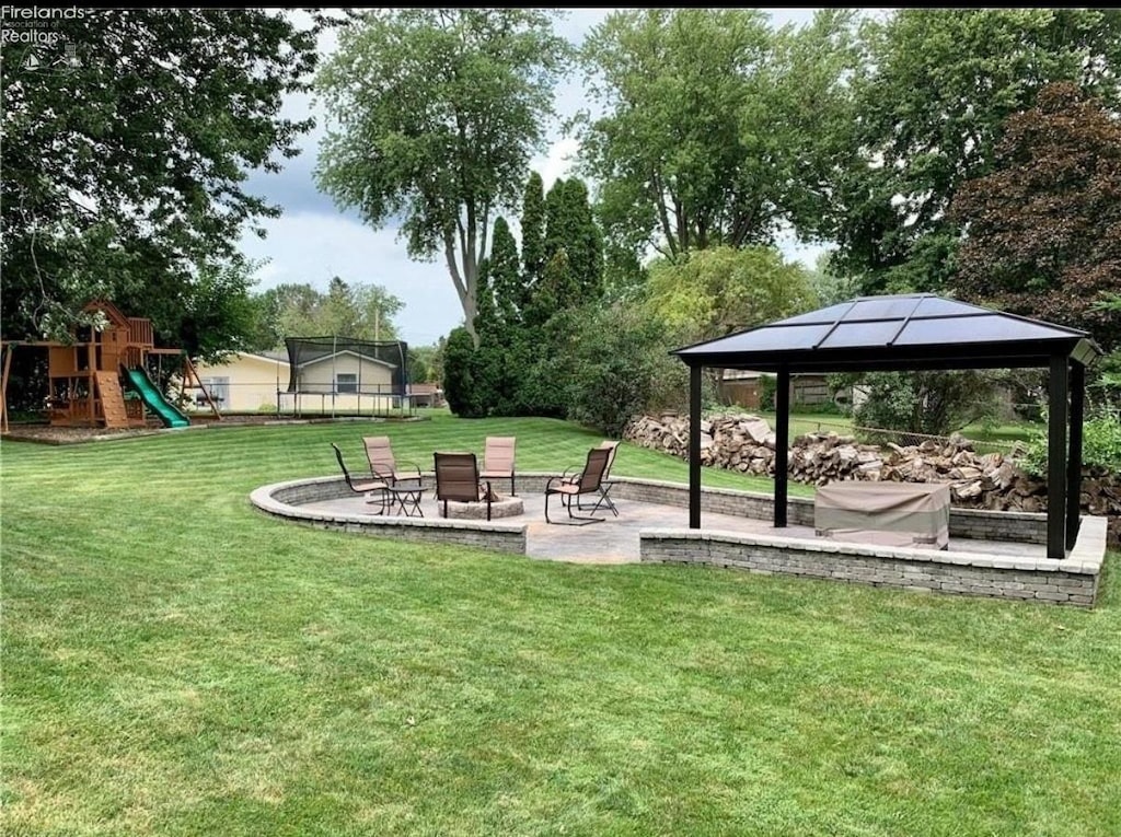 view of yard with a trampoline, playground community, a patio, and a gazebo