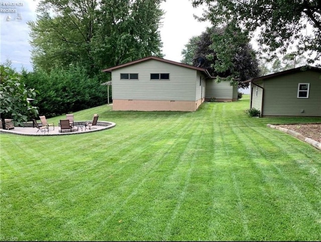 back of property featuring crawl space, a patio area, an outdoor fire pit, and a lawn