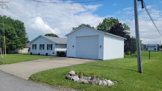 ranch-style house featuring a garage, a front lawn, concrete driveway, and an outbuilding