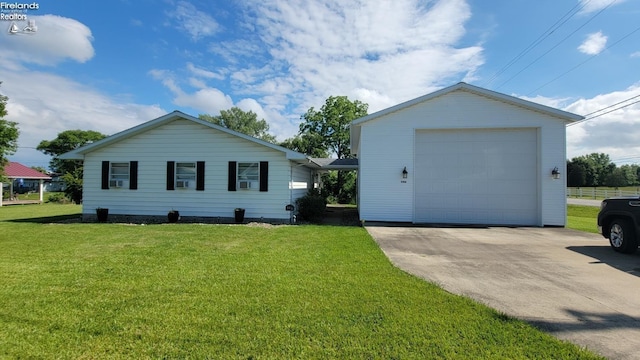 view of front of property featuring a front yard, concrete driveway, and an outbuilding