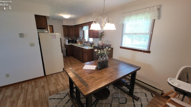 dining space featuring baseboards, baseboard heating, light wood-style flooring, and an inviting chandelier