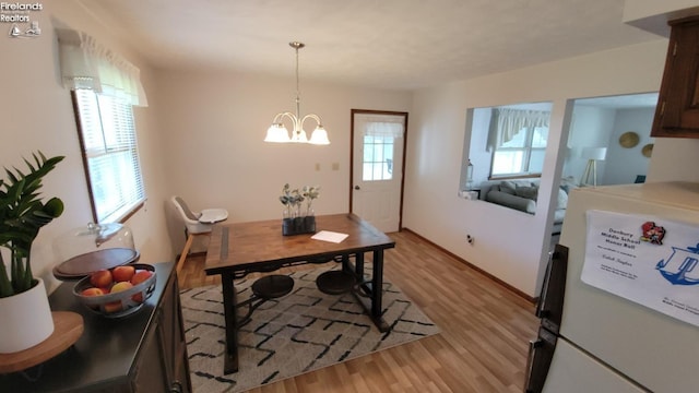 dining space featuring a chandelier, light wood-type flooring, and baseboards