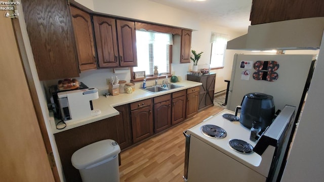 kitchen with a sink, light countertops, freestanding refrigerator, electric range oven, and light wood finished floors